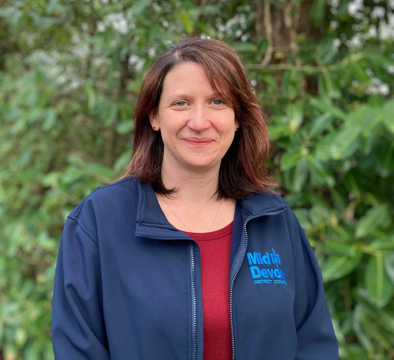 Samantha poses for the camera in front of a bush