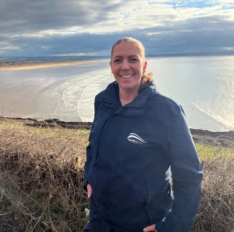 Suse poses in front on a hill with a beach back drop