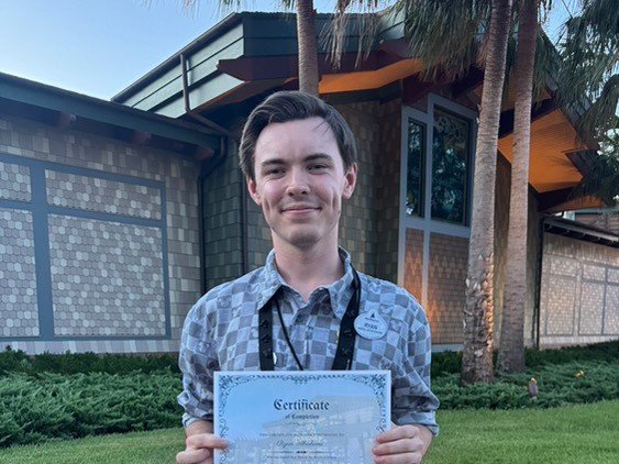 Ryan holding a certificate from Disney World.